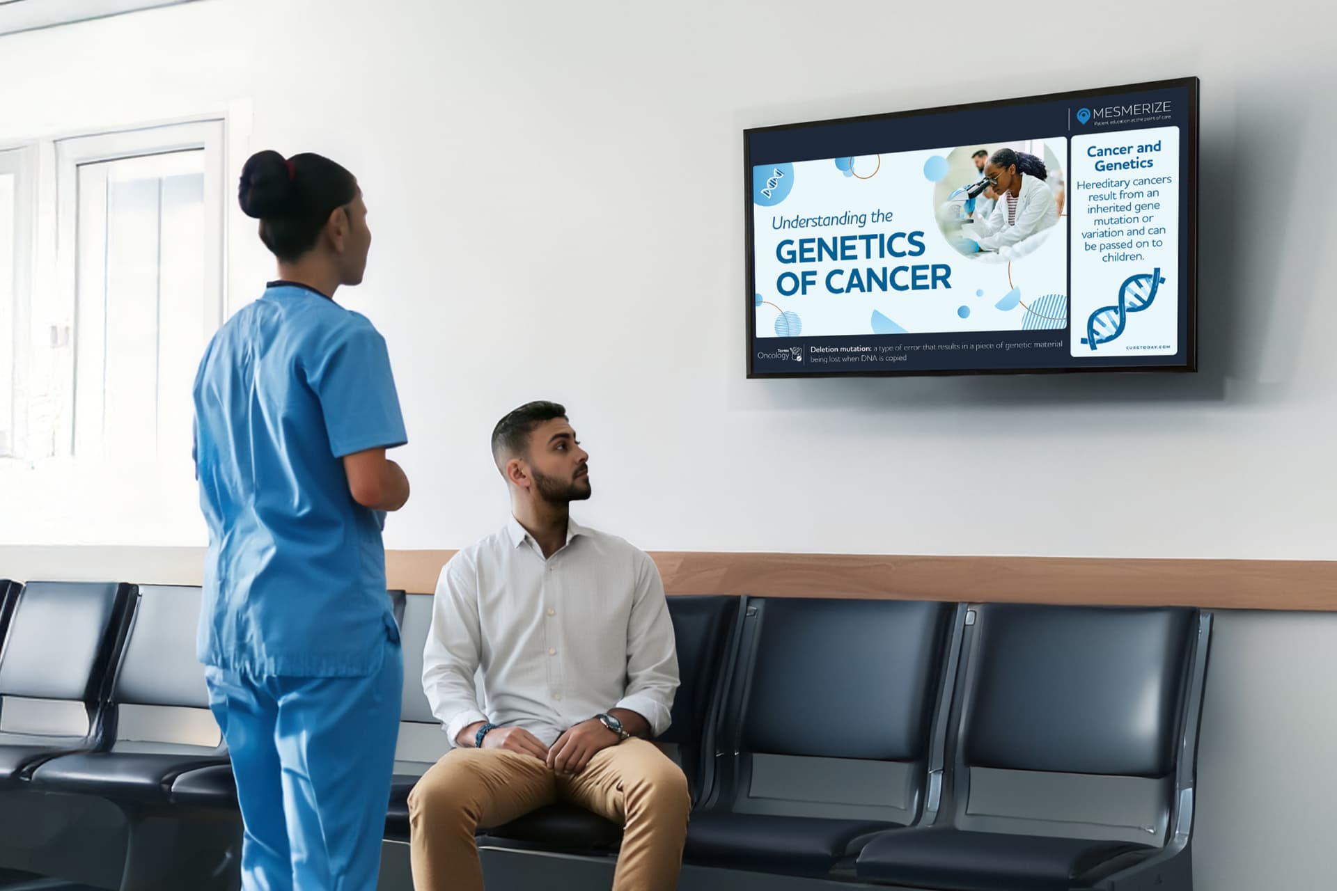 A doctor and a patient looking at a digital screen in a waiting room that has oncology education content on it.