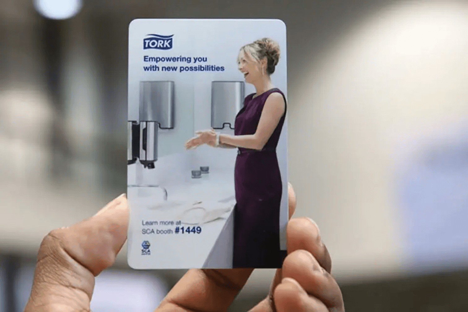 Hotel keycard with an advertisement on it being held by a hand.