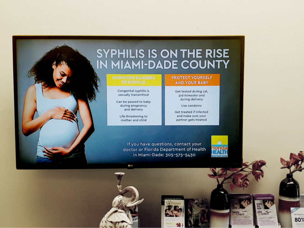 Doctor pointing to information displayed on digital screen for patient to read.